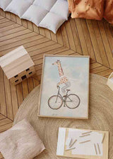 Cuadro con jirafa montando una bicicleta clásica, tonos beige, crema y azul empolvado, con aire tierno y estilo infantil. Disponible en kudeko.com