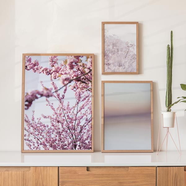 Set aus drei Wandbildern mit unscharfen rosafarbenen Blüten, zarten Zweigen, hellem Hintergrund, Rosa Weiß und Malve, sanfte botanische Komposition im floralen Stil. Erhältlich auf kudeko.com