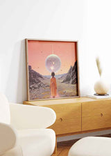 Surrealistisches Wandbild mit einer Frau, die eine leuchtende Kugel in einer Wüstenlandschaft betrachtet. Erhältlich auf kudeko.com