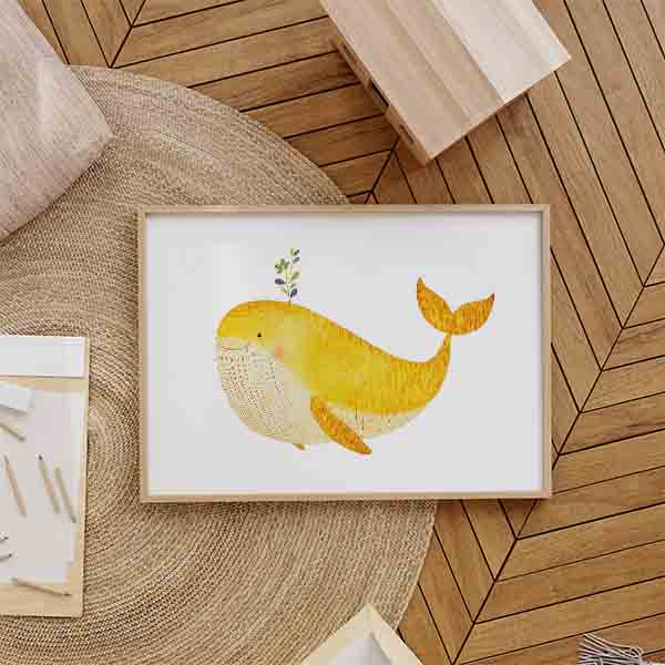 Cuadro horizontal con ballena amarilla de gran tamaño, vientre crema, brote verde y fondo blanco, en composición suave de estilo infantil. Disponible en kudeko.com