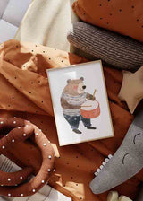 Cuadro de oso infantil tocando un tambor naranja, con ropa de rayas en beige, marrón, azul marino y estilo infantil. Disponible en kudeko.com