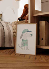 Tableau encadré avec chien sympathique, casquette bleue, pull vert d’eau, détails gris et beiges, fond blanc et style enfantin doux. Disponible sur kudeko.com