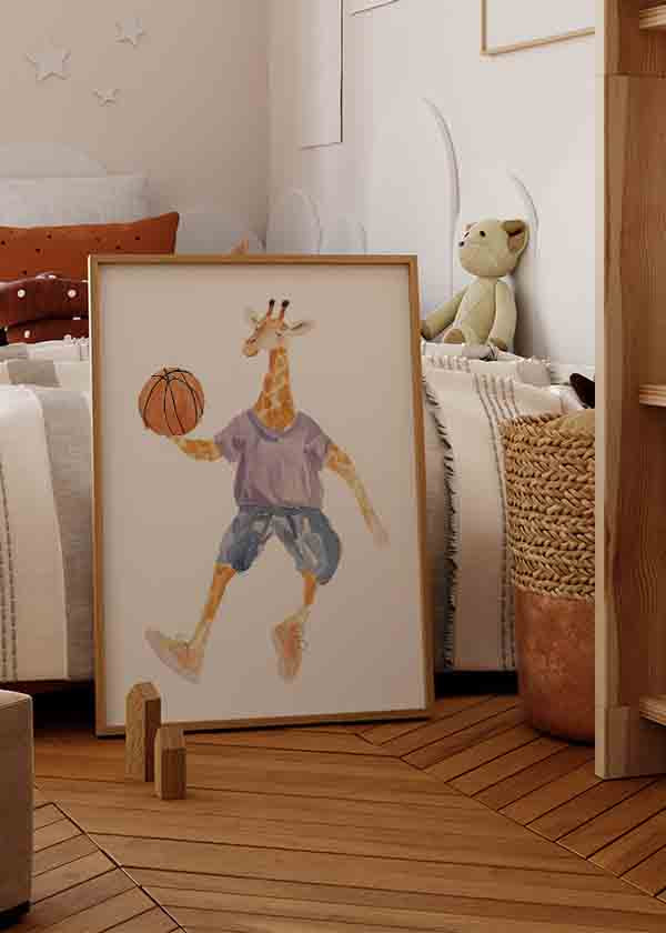 Quadro emoldurado com girafa a jogar basquetebol, bola laranja, camisola lilás, calças azuis, fundo branco e estilo infantil em tons suaves. Disponível em kudeko.com