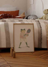 Tableau avec grenouille joueuse de tennis, pull rose à pois, pantalon clair, raquette rouge, fond crème et style enfantin aux tons vert olive, blanc et noir. Disponible sur kudeko.com