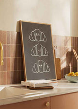Cuadro cuadrado minimalista con adorables croissants felices. Disponible en kudeko.com