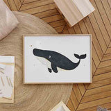 Horizontales Wandbild mit dunkelblauem Wal auf weißem Hintergrund, kleinen goldenen Details und kindlichem Illustrationsstil mit klaren Formen und ruhiger Ausstrahlung. Erhältlich auf kudeko.com