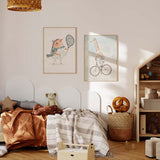 Cuadro con jirafa montando una bicicleta clásica, tonos beige, crema y azul empolvado, con aire tierno y estilo infantil. Disponible en kudeko.com