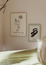 Cuadro con gato negro estilizado sobre fondo crema, borde ajedrezado azul claro, detalles faciales blancos y rosa, de estilo vintage. Disponible en kudeko.com