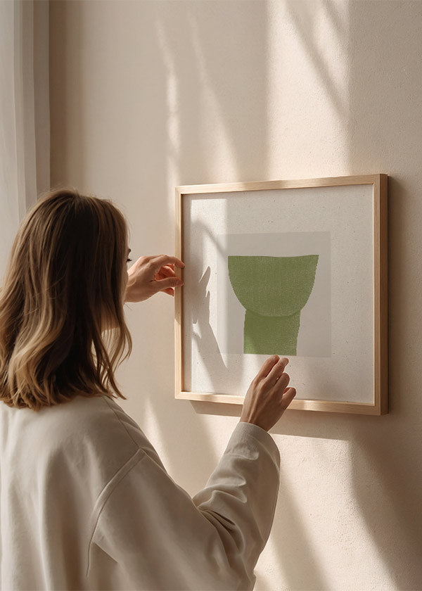 Quadratisches Wandbild mit abstrakter botanischer Form in Olivgrün, hellbeigem strukturiertem Hintergrund, klarer Komposition und minimalistischem Stil für moderne Räume. Erhältlich auf kudeko.com