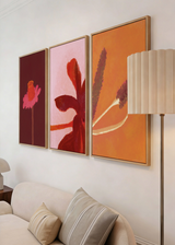 Composición de tres cuadros decorativos de estilo minimalista y orgánico, ramas florales sobre fondo naranja cálido, modelo Espigas al Sol