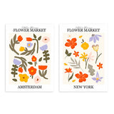 Ensemble de deux tableaux avec fleurs et feuilles décoratives en orange, jaune, lilas, rose et vert olive, style floral avec titres Flower Market de villes sur fond clair. Disponible sur kudeko.com