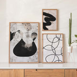 Conjunto de tres cuadros con formas abstractas negras, grises y beige, manchas orgánicas, siluetas redondeadas y líneas curvas sobre fondo claro, de estilo abstracto. Disponible en kudeko.com
