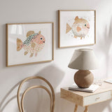 Horizontales Wandbild mit kleinem rundlichem Fisch in zartem Rosa, Weiß, Aquagrün, goldfarbenen Details, dekorativen Flecken und kindlichem Stil fürs Kinderzimmer. Erhältlich auf kudeko.com