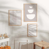 Quadro emoldurado com três formas semicirculares brancas alinhadas sobre fundo taupe suave, linhas finas centrais e composição geométrica equilibrada de estilo depurado. Disponível em kudeko.com