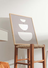 Quadro emoldurado com três formas semicirculares brancas alinhadas sobre fundo taupe suave, linhas finas centrais e composição geométrica equilibrada de estilo depurado. Disponível em kudeko.com