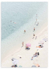 Quadro com vista aérea de praia com areia branca, água turquesa clara, banhistas dispersos, guarda-sóis em tons suaves e estilo fotográfico luminoso. Disponível em kudeko.com