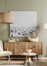 Cuadro cuadrado con escena de playa en blanco y negro, arena clara, horizonte difuso y pequeñas siluetas humanas dispersas, de estilo blanco y negro. Disponible en kudeko.com