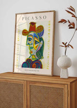 Quadro emoldurado com retrato cubista de mulher, rosto geométrico, fundo creme, tons de azul, amarelo, vermelho, verde e violeta, em estilo de ilustração contemporânea. Disponível em kudeko.com