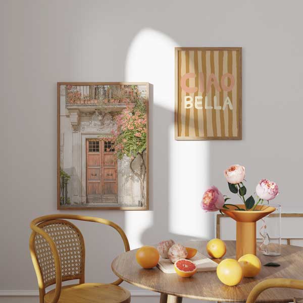 Conjunto de dos cuadros con frase CIAO BELLA, franjas beige y marrón, fachada italiana con puerta de madera y flores rosadas, estilo vintage. Disponible en kudeko.com