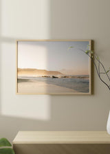 Cuadro horizontal de playa en Costa Rica con olas suaves, arena clara, bruma dorada, montañas al fondo y estilo fotográfico en tonos beige y azul grisáceo. Disponible en kudeko.com