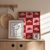 Cuadro con cuadrícula de sombreros vaqueros en bloques rosa y rojo terracota, composición gráfica de aire retro y estilo pop art. Disponible en kudeko.com