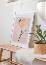 Tableau avec fleur abstraite, tige verte, filaments jaunes, détails bruns et feuilles blanches sur fond rose poudré, dans un style floral contemporain. Disponible sur kudeko.com
