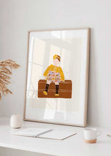 Quadro com menina sentada sobre uma arca castanha, casaco amarelo, vestido floral, fundo bege e estilo ilustrado suave para quarto infantil. Disponível em kudeko.com