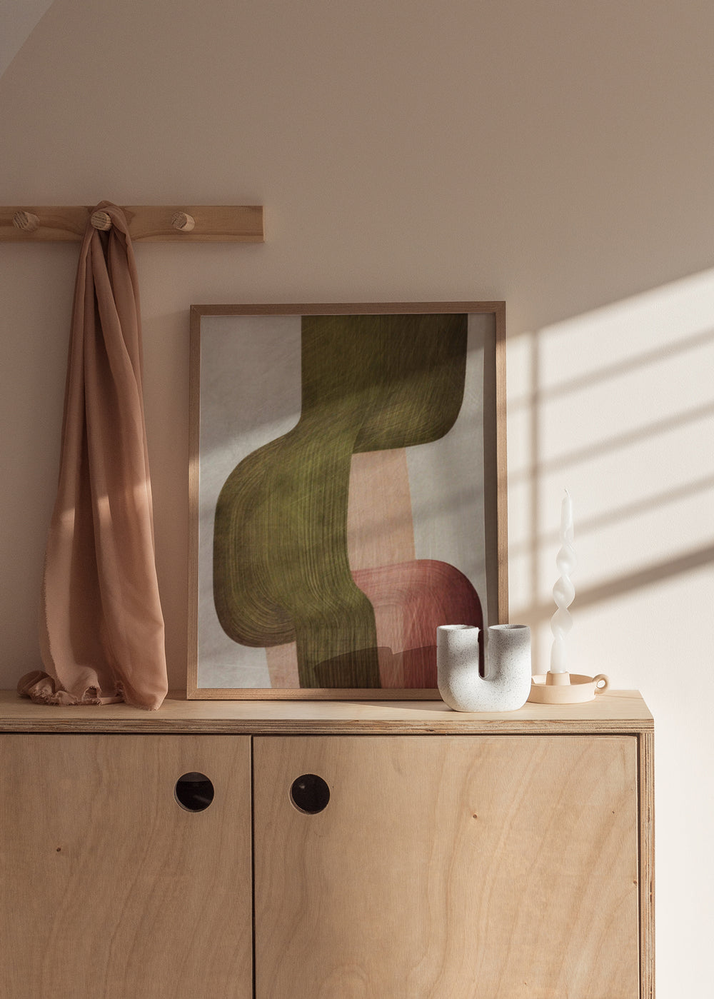 Gerahmtes abstraktes Wandbild mit geschwungenen Formen in Olivgrün, hellem Beige, Altrosa und Terrakotta, in einem ausgewogenen abstrakten Stil mit weichen Linien. Erhältlich auf kudeko.com