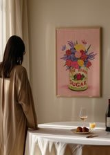Gerahmtes Wandbild mit Blumenstrauß in Rosa, Violett und Gelb in einer Vintage-Dose, vor zartrosa Hintergrund, mit grünen Blättern, kleinen Schmetterlingen und floralem Stil. Erhältlich auf kudeko.com