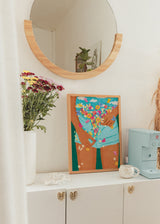 Tableau encadré représentant une figure féminine avec short turquoise, fleurs multicolores, papillons, fond bleu et style illustration aux accents décoratifs. Disponible sur kudeko.com