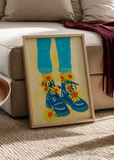 Wandbild mit blauen Stiefeln, gelben Sonnenblumen mit orangefarbenen Mitten, türkisfarbener Hose, cremefarbenem Hintergrund und grafischem Illustrationsstil. Erhältlich auf kudeko.com