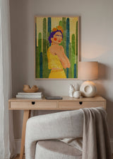 Quadro emoldurado de mulher inspirada em Frida Kahlo com altos cactos verdes, vestido amarelo, flores laranja, fundo creme e estilo de ilustração com inspiração mexicana. Disponível em kudeko.com