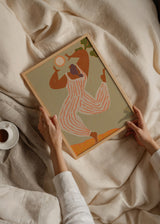 Wandbild mit stilisierter weiblicher Figur, weißem Overall mit korallfarbenen Streifen, heller Sonne, beigem Hintergrund, grünen Details und zeitgemäßem Illustrationsstil mit organischen Formen. Erhältlich auf kudeko.com