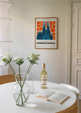 Tableau encadré de la Sagrada Família de Barcelone en tons bleus, entourée de fleurs orange sur fond clair, avec style illustration et composition graphique décorative. Disponible sur kudeko.com