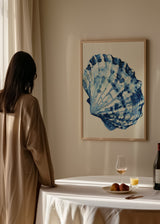 Gerahmtes Wandbild mit einer Meeresmuschel in Marineblau, Hellblau und Weiß, mit organischen Formen auf hellem Hintergrund und illustrativem Stil im Küstenlook. Erhältlich auf kudeko.com