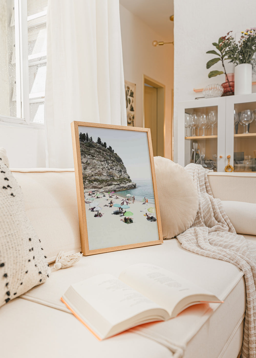 Tableau d’une crique italienne avec falaise rocheuse claire, sable clair, mer bleue paisible et parasols pastel, dans un style photographique au charme côtier et estival. Disponible sur kudeko.com