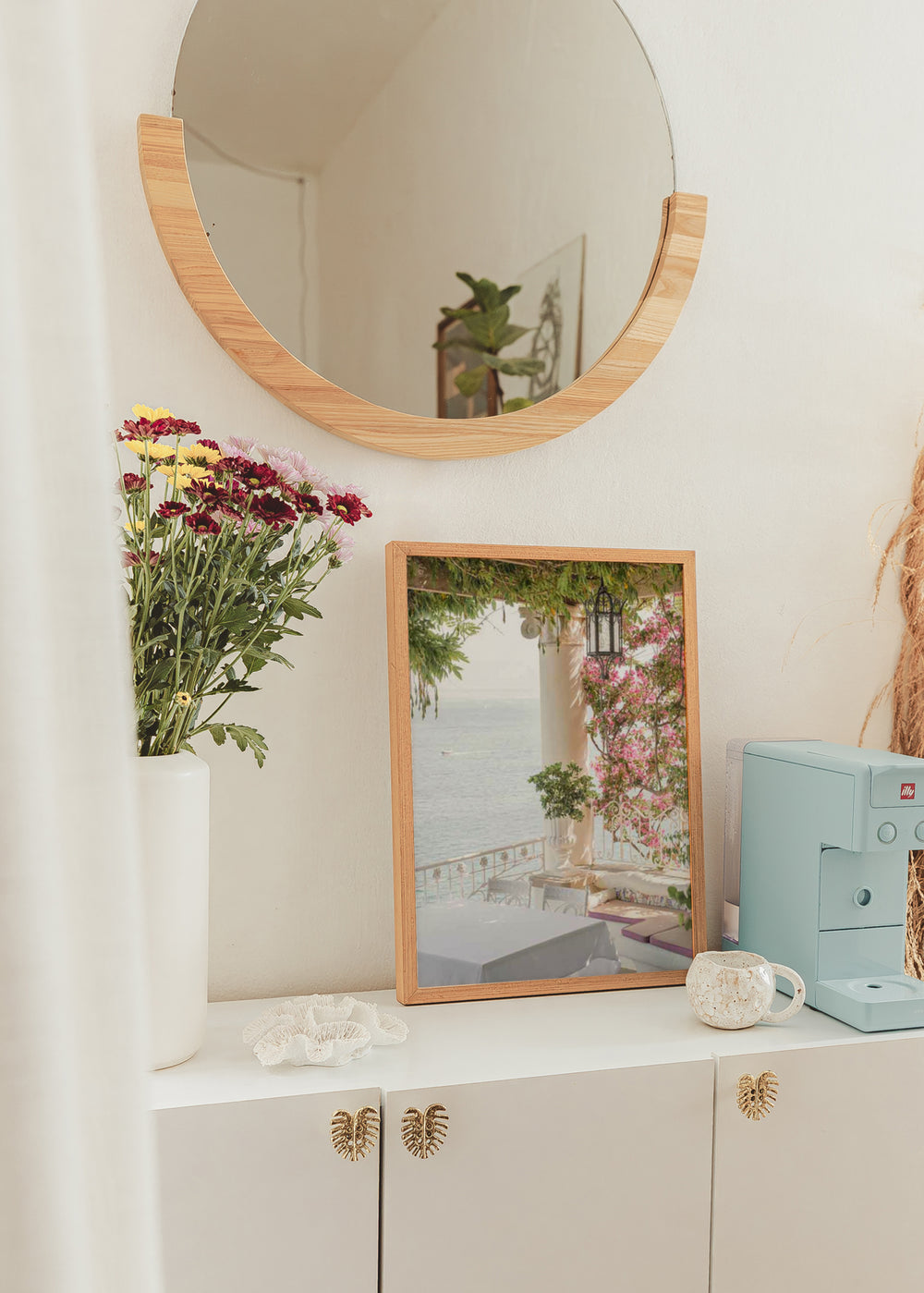 Tableau d’une terrasse méditerranéenne face à la mer avec bougainvilliers roses, colonnes blanches, lanterne noire, végétation verte et lumière douce, dans un style photographique lumineux. Disponible sur kudeko.com