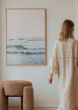 Tableau représentant une mer calme avec vagues douces, écume blanche, rivage clair, ciel rose poudré, tons sable, blanc et vert d’eau, dans un style photographique. Disponible sur kudeko.com