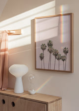 Tableau encadré avec grands palmiers sur fond rose poudré, nuances de vert doux, beige clair et style photographique tropical apaisé et lumineux. Disponible sur kudeko.com
