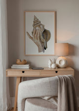 Cuadro decorativo de estilo mar_y_playa y minimalista colocado en salón, mano sosteniendo caracola marina en tonos tierra, modelo Coastal Art Brown II