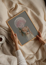 Wandbild mit weiblicher Figur im Küstenstil, großer rosa Muschel, grünem Palmblatt, Kleidung in Sandtönen, grauem Hintergrund und ruhigem Illustrationsstil. Erhältlich auf kudeko.com