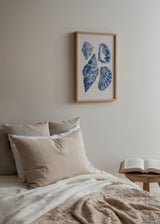 Gerahmtes Wandbild mit vier blauen Muscheln auf hellbeigem Hintergrund, mit küstennaher Komposition, linearen Details und dekorativem Vintage-Stil. Erhältlich auf kudeko.com