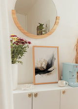 Quadro emoldurado com ramos dourados sobre composição preta fluida, fundo branco quebrado, nuances bege e cinzentas, em estilo abstrato contemporâneo para decoração de parede. Disponível em kudeko.com