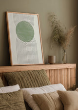 Gerahmtes Wandbild mit großem salbeigrünem Kreis in der Mitte, schwarzen parallelen Schwunglinien, weißem Hintergrund und klarer geometrischer Gestaltung. Erhältlich auf kudeko.com