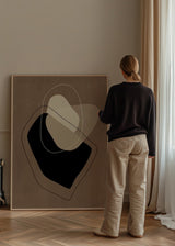 Tableau encadré avec composition abstraite de formes organiques superposées en brun taupe, beige, crème et noir, avec lignes fines claires et foncées, dans un style abstrait épuré. Disponible sur kudeko.com