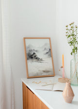 Tableau avec paysage abstrait de montagnes brumeuses, arbres sombres, rive paisible, tons gris, noir et beige clair, dans un style épuré et contemporain. Disponible sur kudeko.com