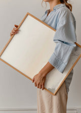 Tableau de paysage avec lever de soleil brumeux, soleil discret, montagnes douces, eau calme et silhouettes végétales en gris, beige et crème, dans un style nature et paysage. Disponible sur kudeko.com