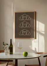 Quadro quadrado minimalista com adoráveis croissants felizes. Disponível em kudeko.com