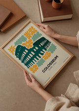 Tableau encadré avec illustration du Colisée de Rome en bleu pétrole, fleurs moutarde, formes organiques vert sauge, fond clair et style illustré moderne. Disponible sur kudeko.com
