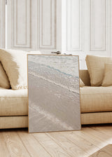 Quadro emoldurado de beira-mar com espuma branca, areia bege, subtis tons azul-turquesa e estilo natureza e paisagem sereno. Disponível em kudeko.com